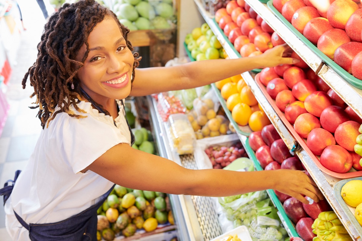 woman working at fruit department at grocery store