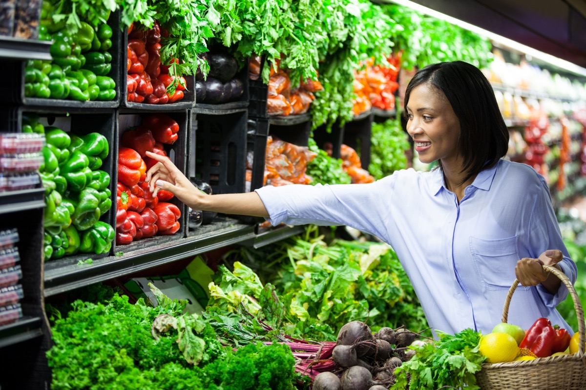 Woman buying vegetables in organic section of supermarket